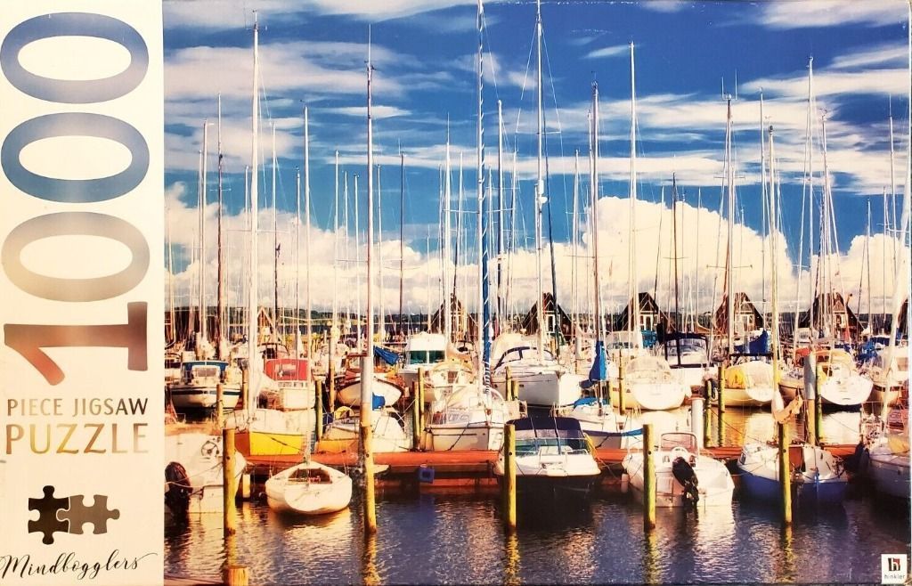 A densely packed marina filled with white sailboats against a vibrant blue sky with fluffy white clouds.