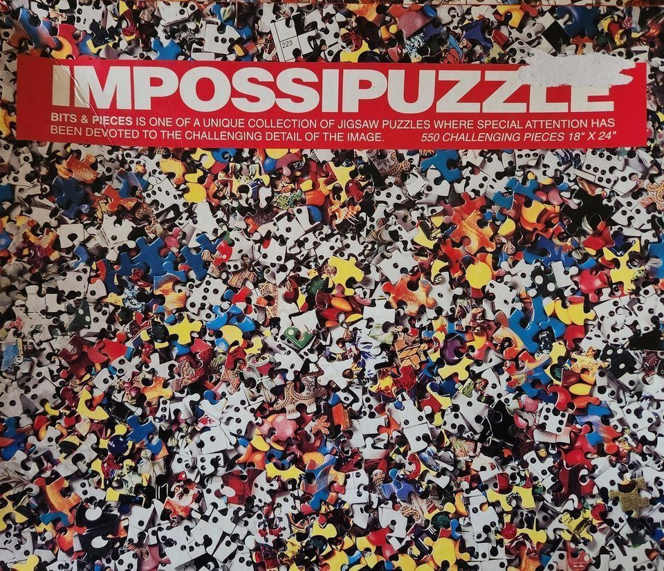 A dense, chaotic pile of scattered jigsaw puzzle pieces in various shapes, sizes, and colors.