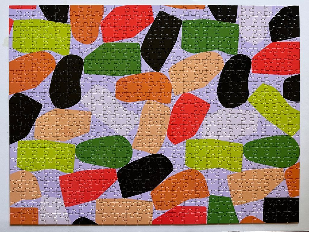 An abstract pattern of varied colorful organic shapes against a light purple background.