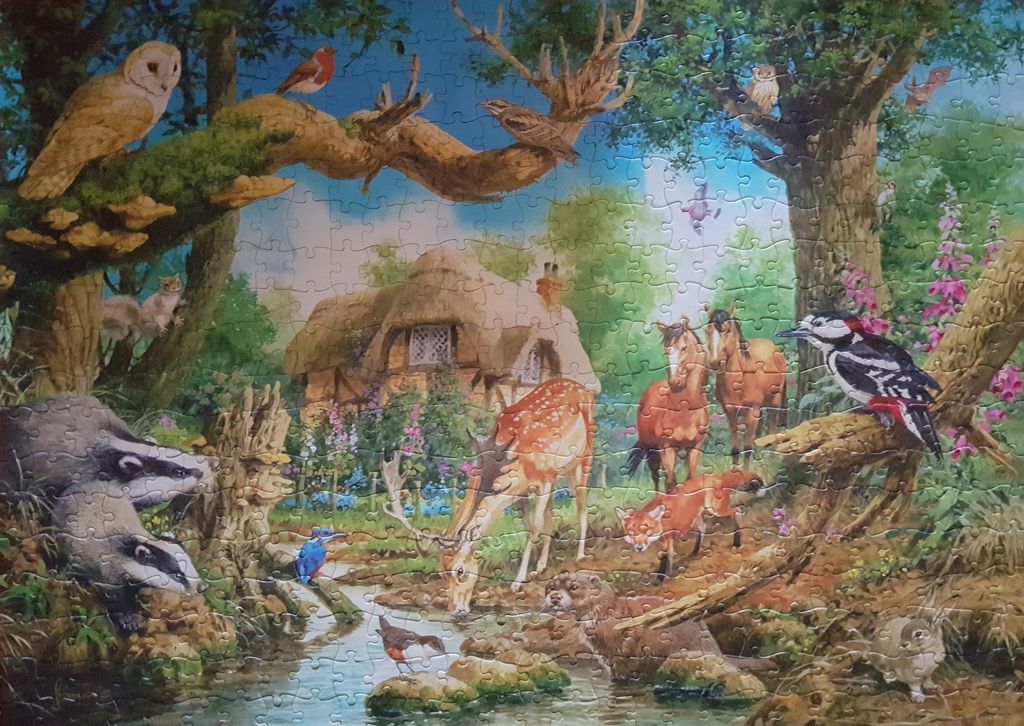 A lush woodland scene featuring a thatched cottage, a stream, and many animals including a deer, badgers, and birds.