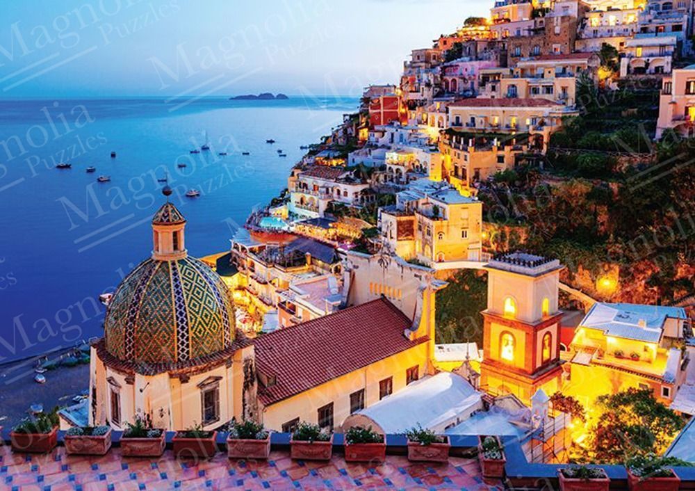 Elevated view of a Mediterranean coastal town at twilight with a tiled dome church in the foreground.