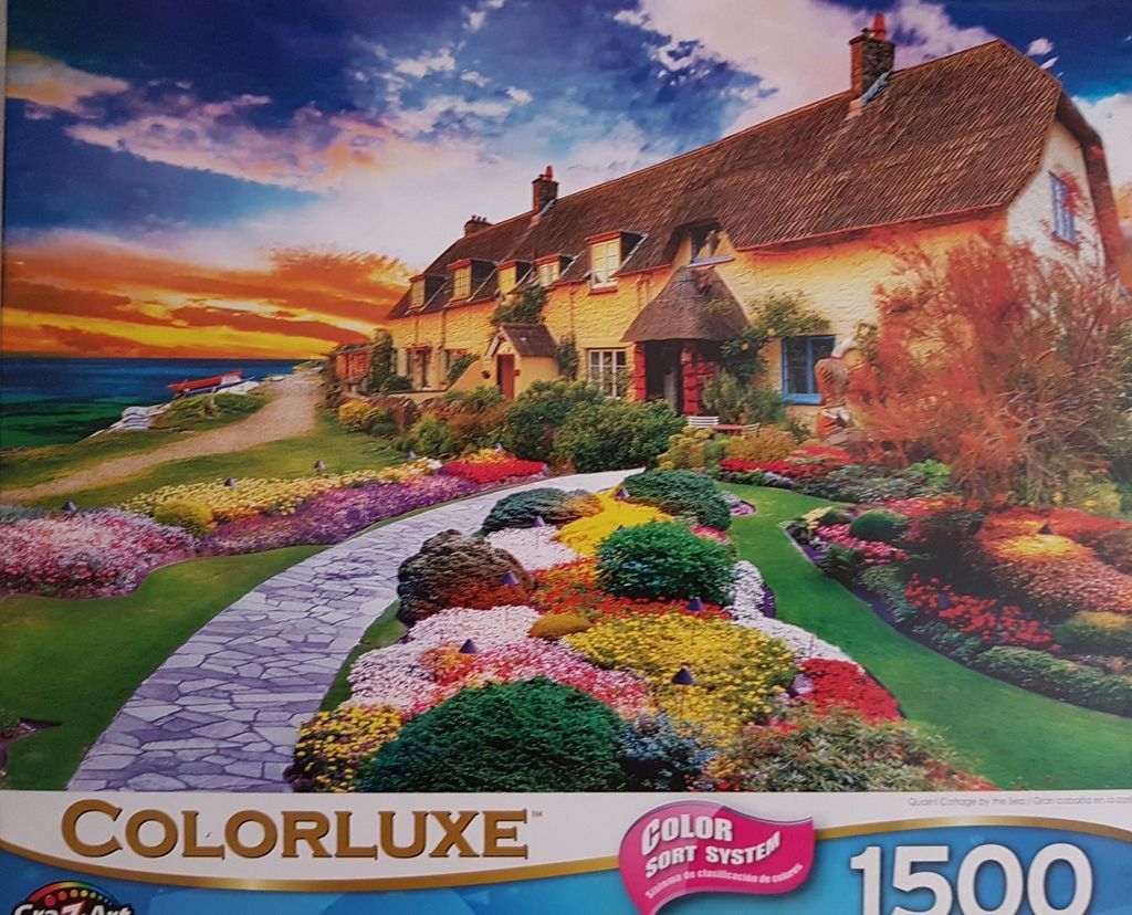 A thatched-roof cottage overlooks the ocean during a vibrant sunset over a colorful garden path.