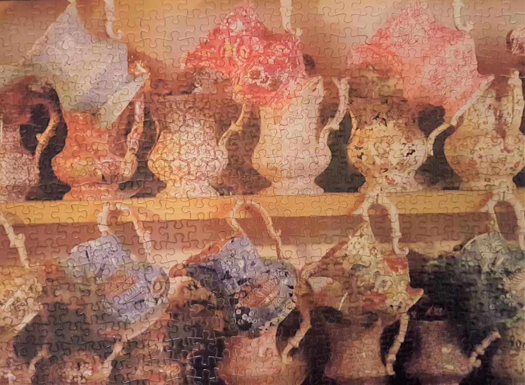 An arrangement of antique ceramic pitchers and jugs displayed on wooden shelves.