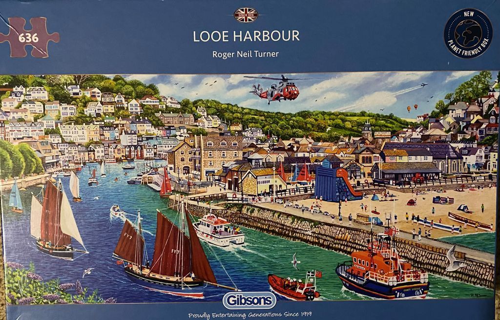 Painting of Looe Harbour with boats, a beach, and a helicopter flying over town buildings on a hillside.