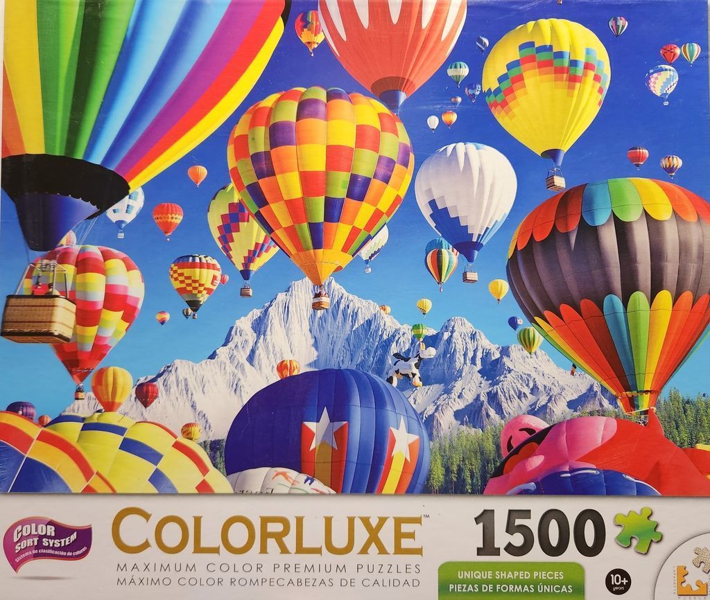 Many colorful hot air balloons floating over a snow-capped mountain range under a clear blue sky.
