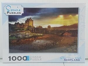 A dramatic sunset over Eilean Donan Castle in Scotland with a stone bridge in the foreground.