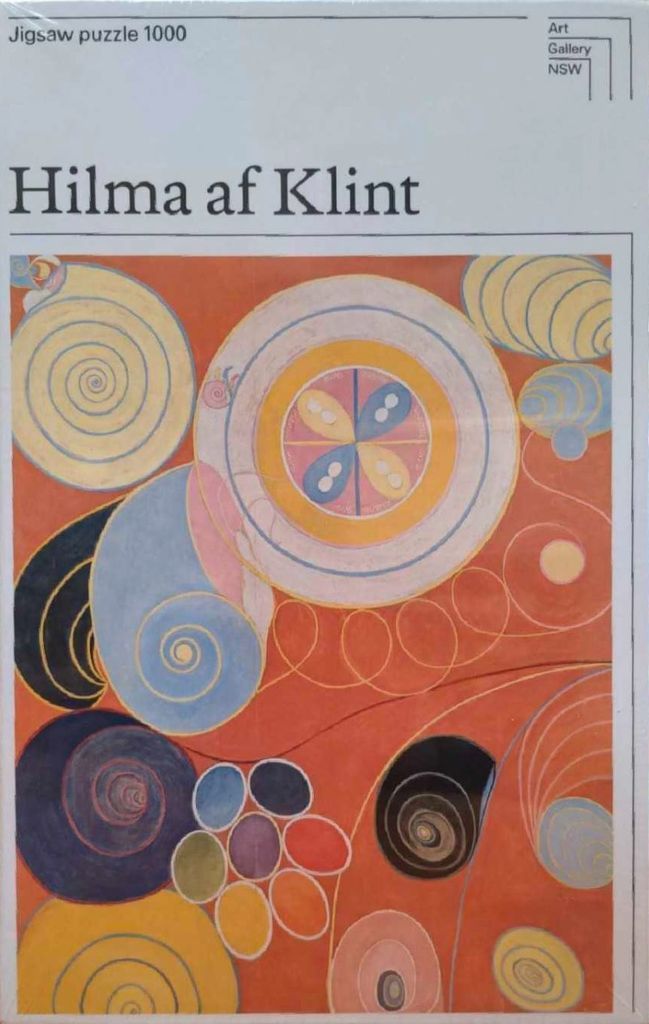 Abstract painting with concentric circles, spirals, and organic shapes in yellow, blue, and pink against a terracotta backgro