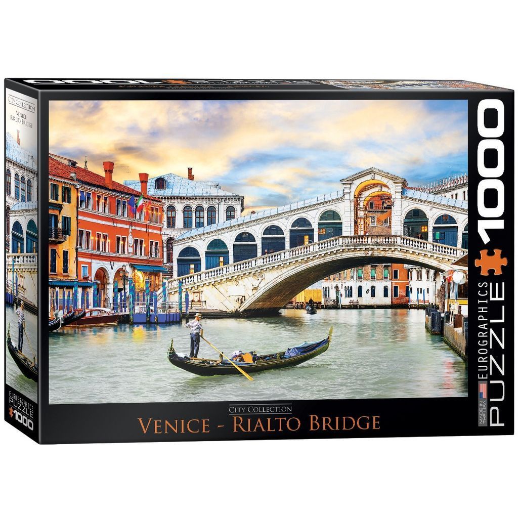 A gondolier rowing a gondola on the Grand Canal in front of the Rialto Bridge in Venice at sunset.