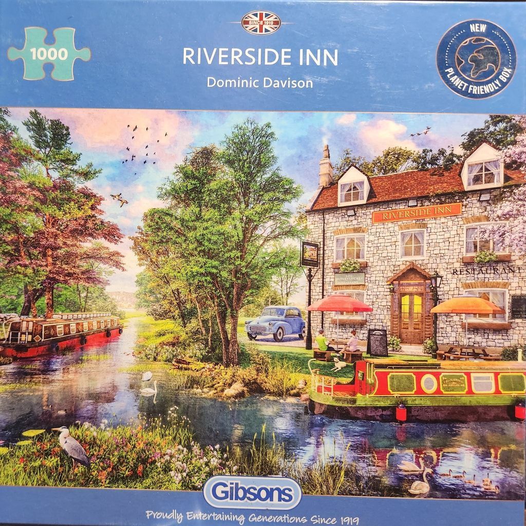 An idyllic riverside inn with a stone building, colorful canal boats, and a lush garden setting at sunset.