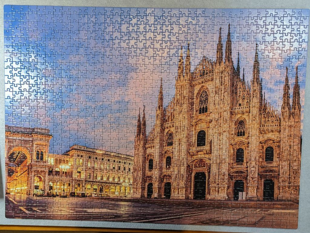 The ornate facade of Milan Cathedral at dusk with the Galleria Vittorio Emanuele II nearby.