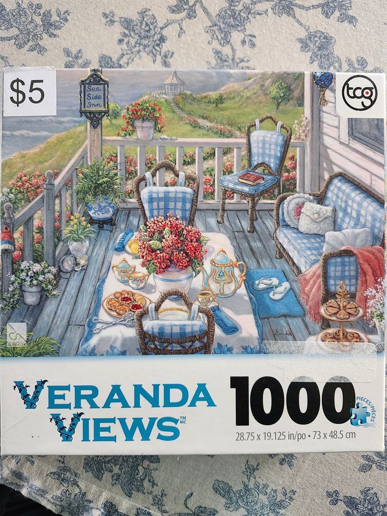 A peaceful coastal porch scene featuring a table set for tea surrounded by wicker chairs with blue-and-white cushions.