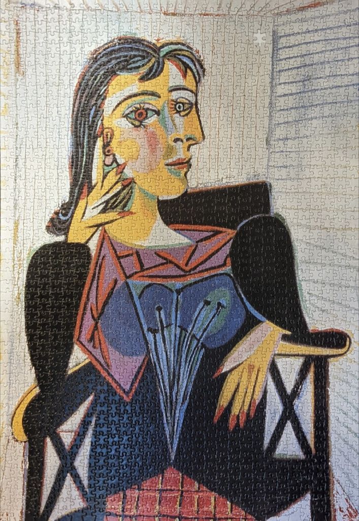 A Cubist portrait of a woman with dark hair sitting in a chair, painted in the style of Pablo Picasso.