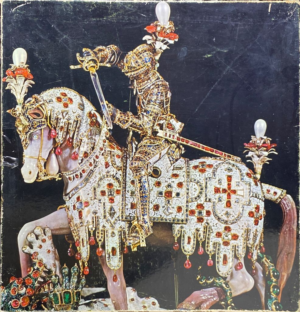 Jeweled figurine of a knight in armor on horseback, set against a black background.
