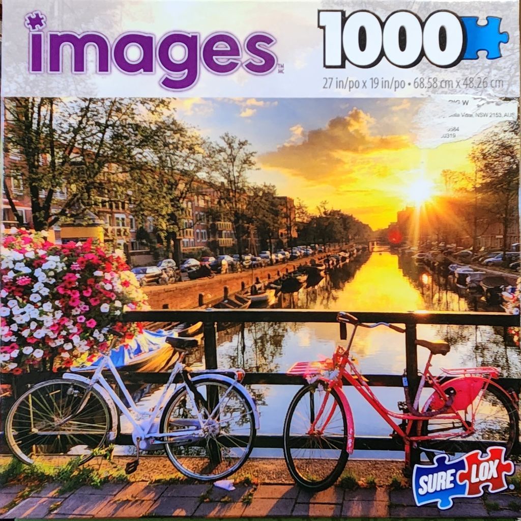 Two bicycles parked on a canal bridge in Amsterdam at sunset with a large bouquet of flowers