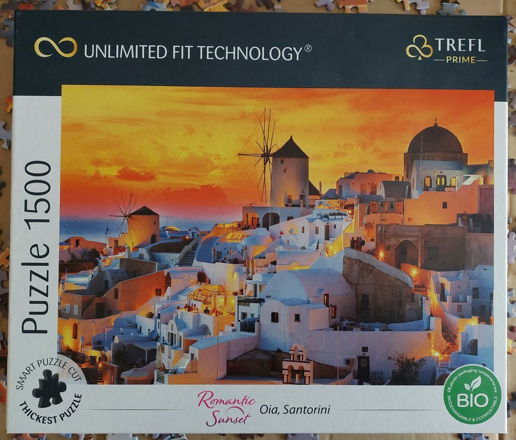 Oia, Santorini at sunset with traditional white buildings and windmills glowing in golden light.