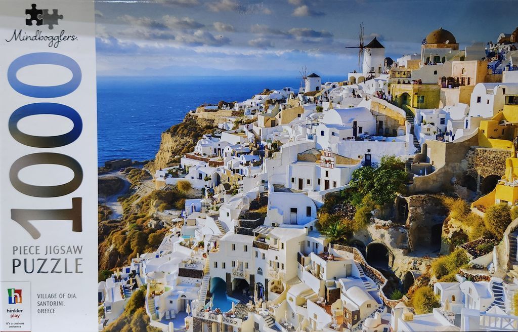 A scenic photograph of the white-washed buildings and blue domes of Oia, Santorini, overlooking the Aegean Sea.