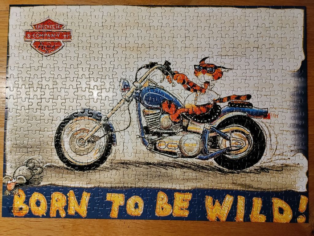 A cartoon illustration of a tiger wearing sunglasses riding a blue motorcycle with the text BORN TO BE WILD!