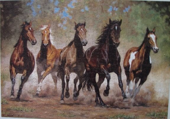 Five horses running in a line through a misty, sunlit forest