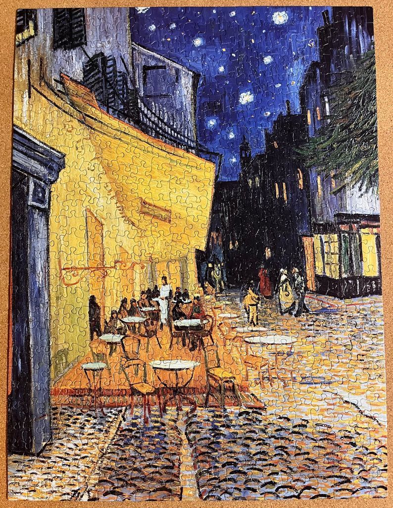 A reproduction of Van Gogh's Cafe Terrace at Night, showing a vibrant yellow cafe terrace under a starry blue night sky.