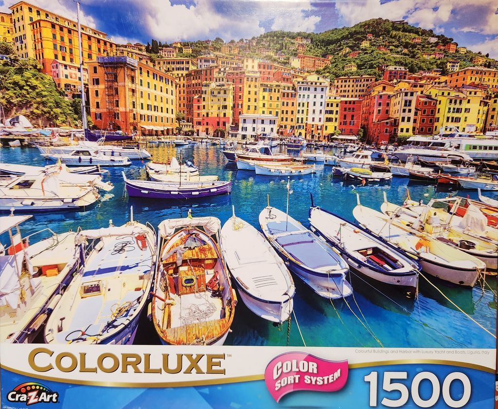 A sunny Italian harbor scene in Liguria with colorful buildings clustered on a hillside overlooking boats.