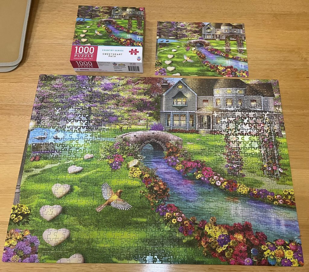An idyllic garden scene featuring a stone house, a winding stream, and heart-shaped stepping stones.