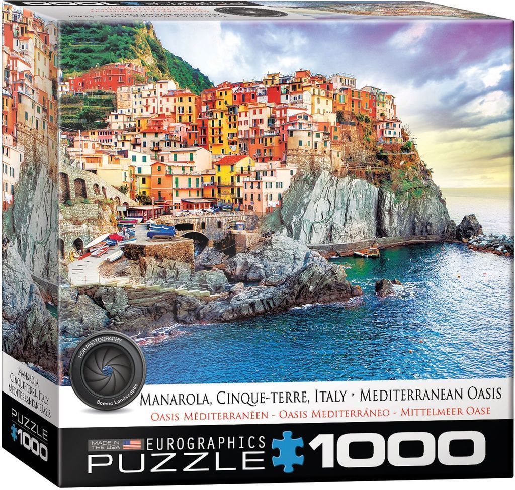 A panoramic landscape photograph of Manarola in Cinque Terre, Italy, with colorful houses built into a steep cliffside.