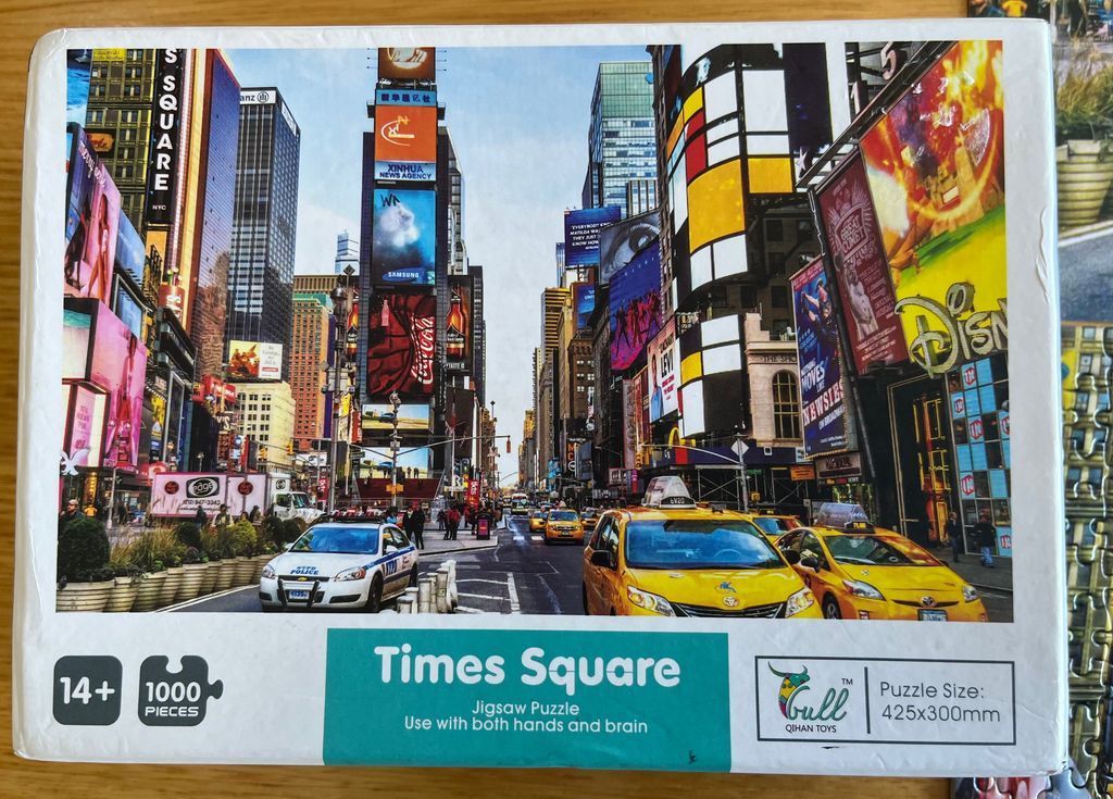 A street-level view of Times Square in New York City with yellow taxis and large advertising billboards.