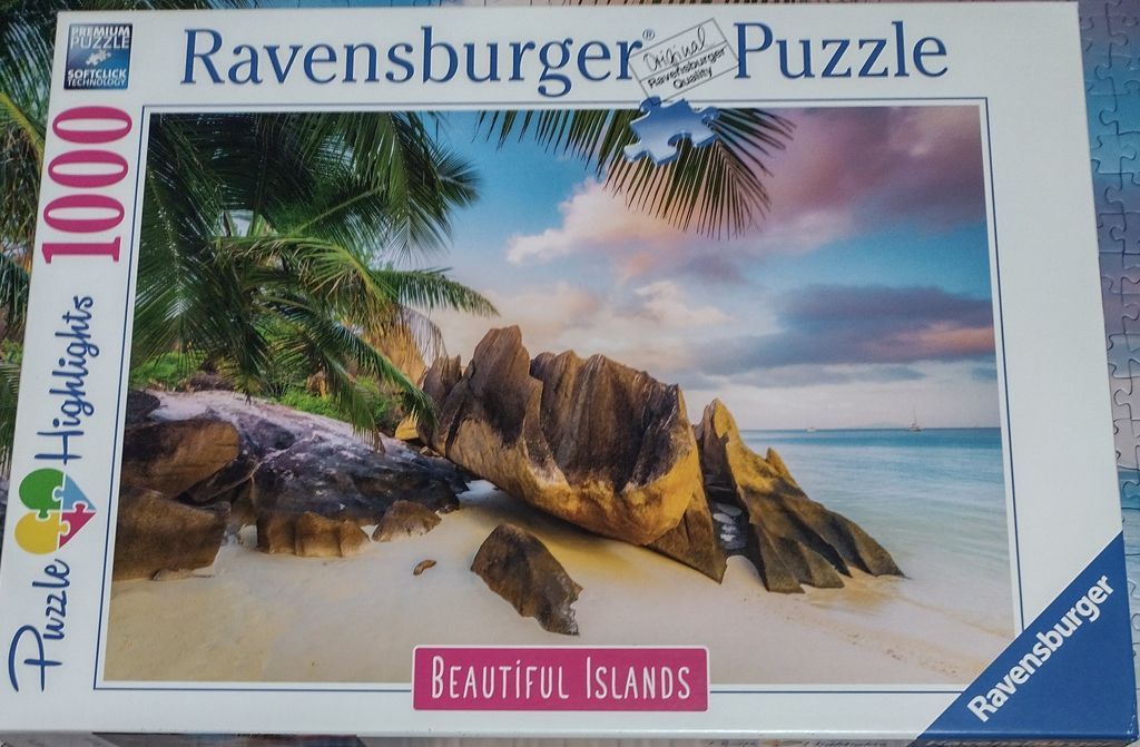 A tropical beach scene at sunset featuring weathered granite boulders and palm fronds.
