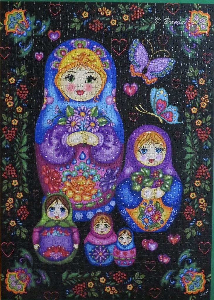 A whimsical illustration of five nested dolls surrounded by floral motifs, butterflies, and small heart shapes on black.