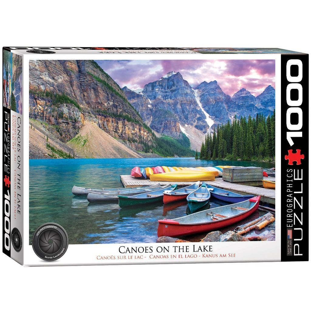 A scenic photograph of several colorful canoes docked at a wooden pier on a lake with towering mountains in the background.