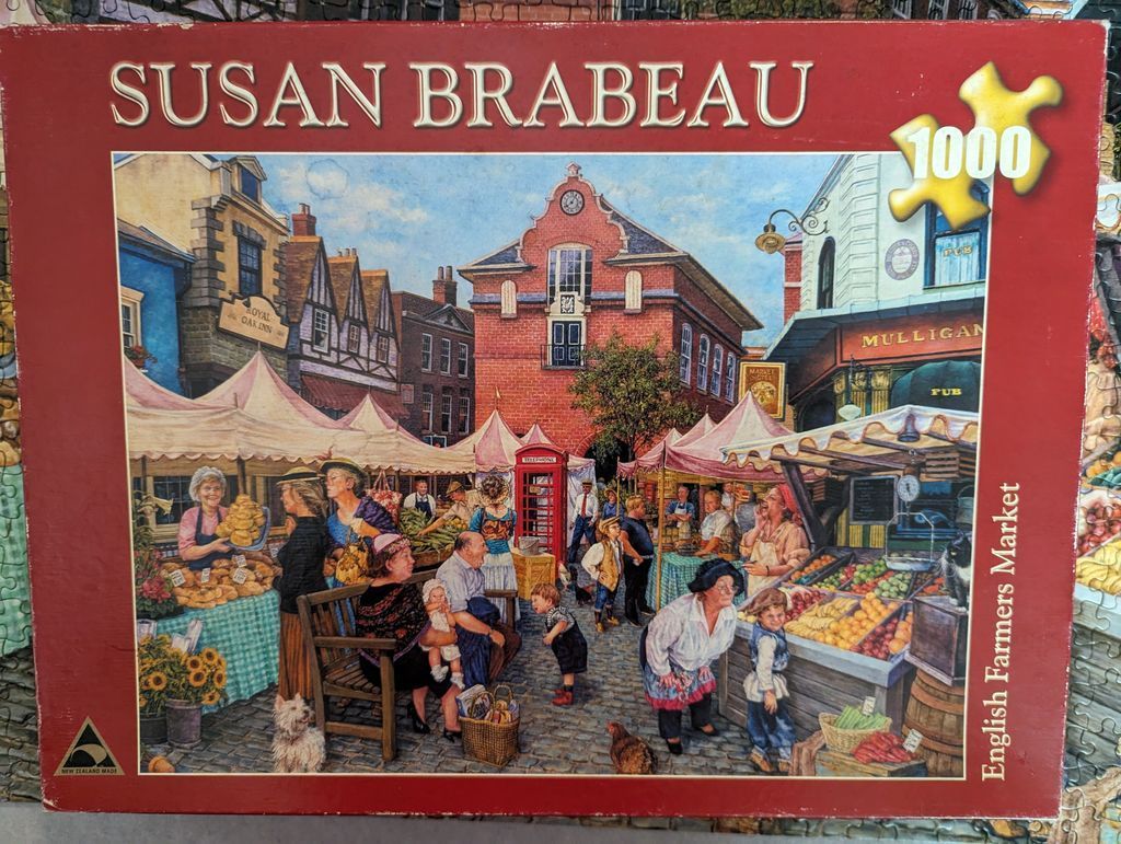 Painting of a bustling English farmers market with stalls, shoppers, and a red telephone box in a historic town square.