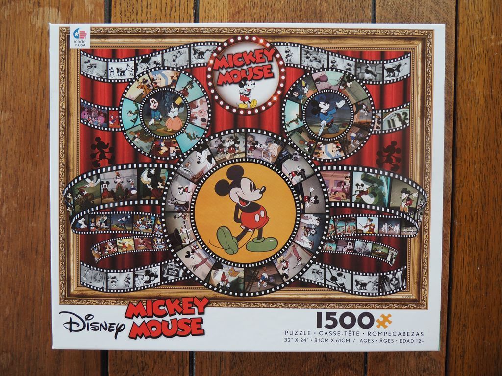 Collage of Mickey Mouse film reels arranged in the shape of Mickey's iconic silhouette against a red curtain background.