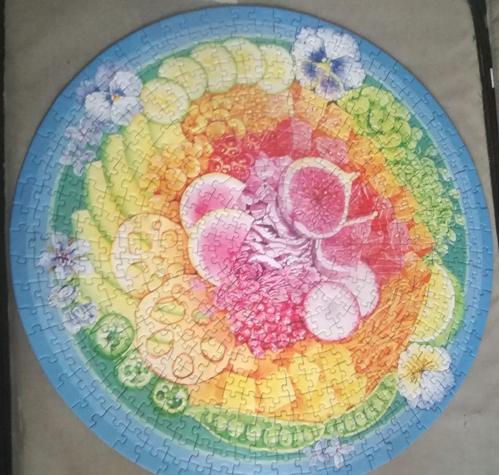Circular illustration of concentric circles of sliced fruit, vegetables, and pansy flowers in a rainbow spectrum.
