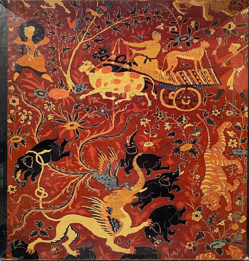 An intricate tapestry-style illustration of stylized animals, hunters, and floral motifs in deep red, yellow, and black.