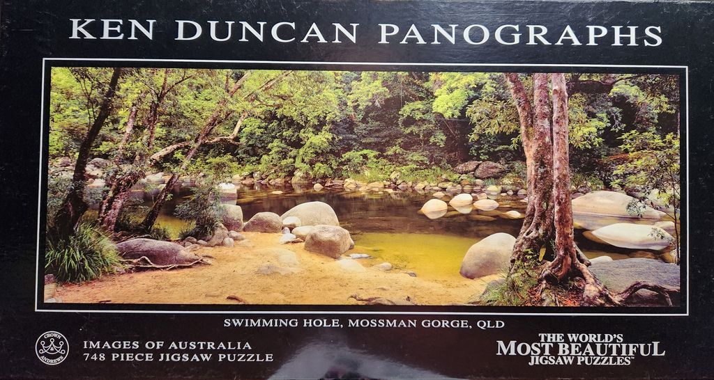 A scenic photograph of a tropical swimming hole at Mossman Gorge surrounded by lush green trees and smooth rocks.