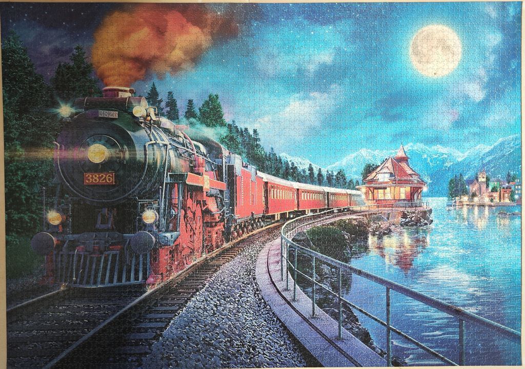 A vintage steam locomotive pulling red passenger cars along a moonlit lakeside railway.