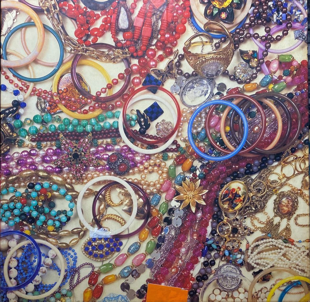A dense, colorful collection of scattered vintage costume jewelry, including bangles, beaded necklaces, and brooches.