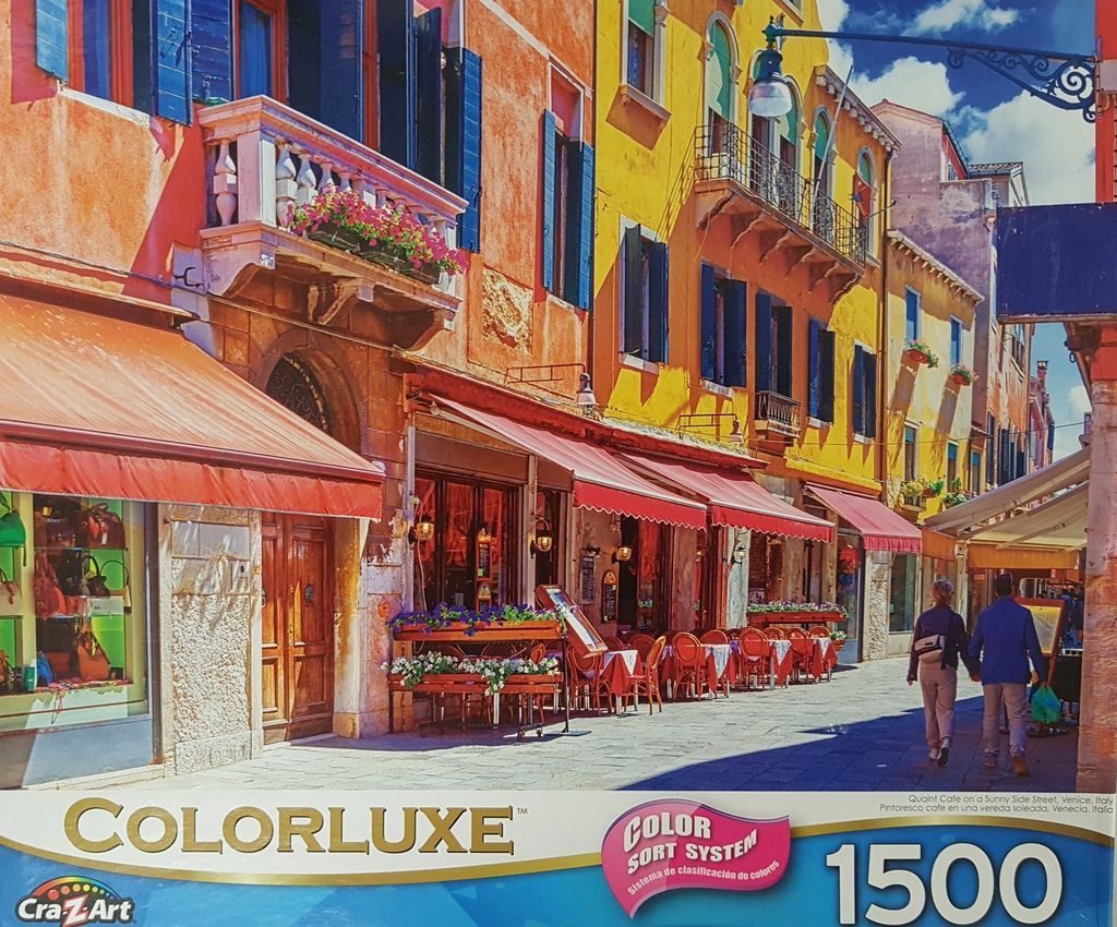 A sunny, colorful street scene in Venice, Italy with outdoor cafe seating and vibrant Mediterranean architecture.