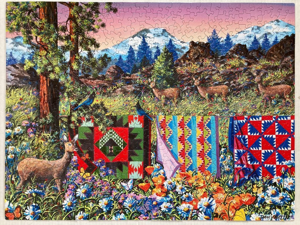 An illustration of three deer in a wildflower meadow next to colorful hanging quilts against a mountain backdrop.