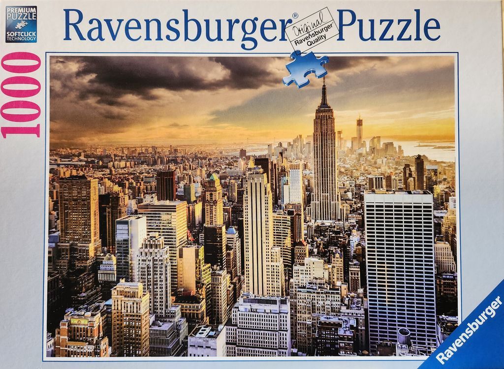Aerial view of the New York City skyline at sunset under a dramatic, cloudy sky.