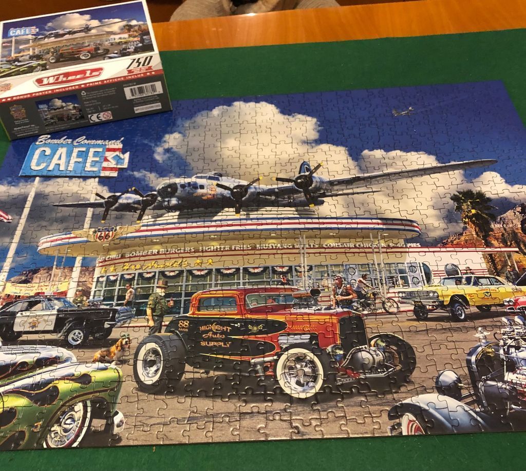 A vintage-style illustration of a Bomber Command Cafe featuring classic hot rods and a B-17 bomber plane on the roof.