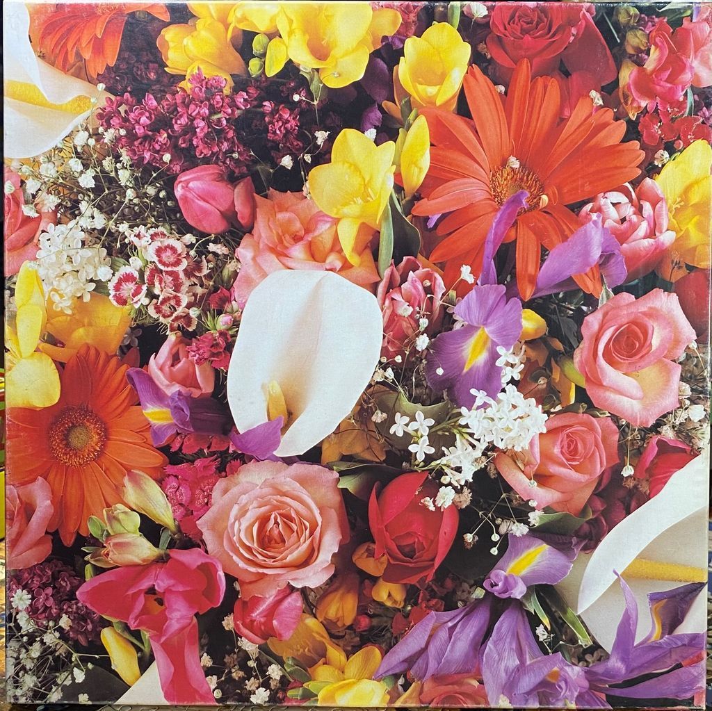 A dense, vibrant arrangement of mixed flowers including lilies, roses, gerbera daisies, and irises.