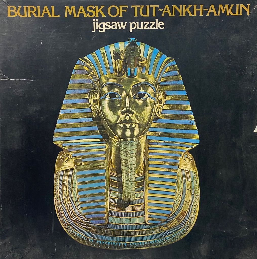 Front-facing close-up photograph of the golden burial mask of Tutankhamun on a black background.