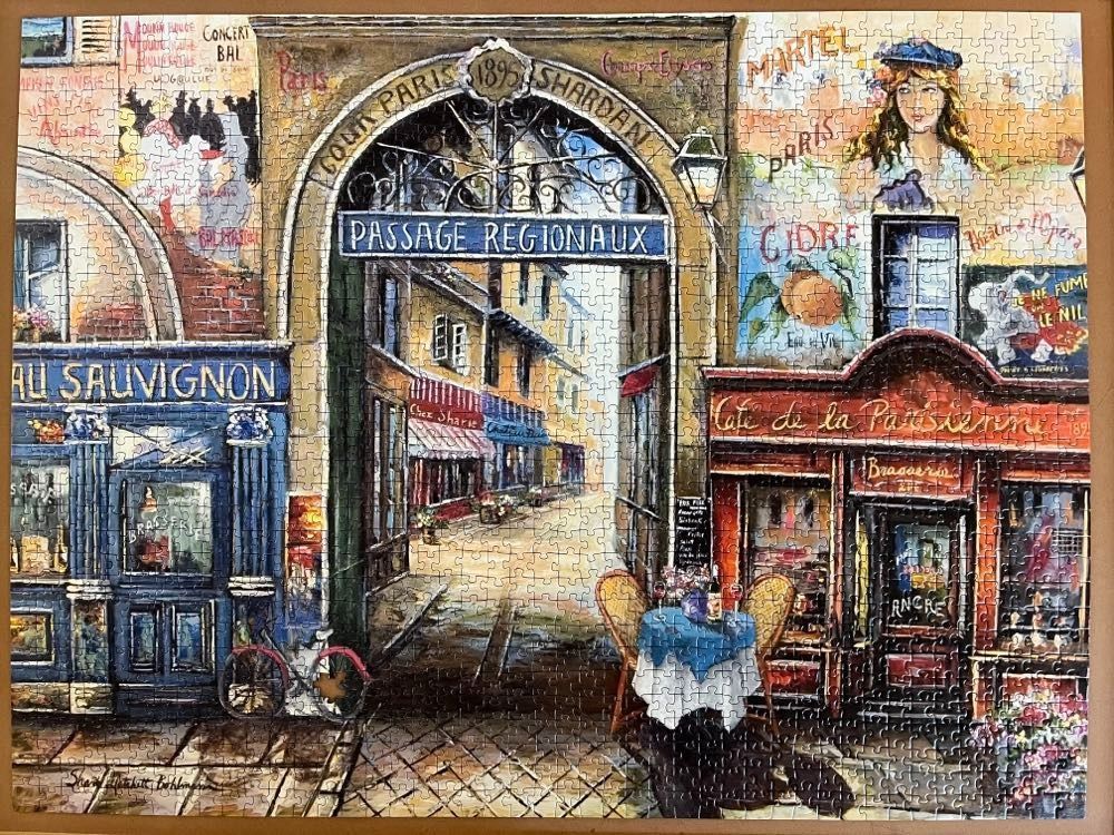 A vintage street scene in Paris featuring a stone archway, a cafe terrace, and painted advertisements on building walls.