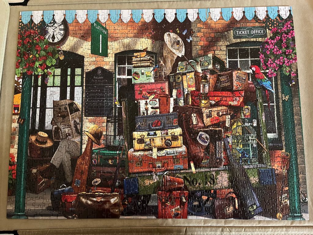 An illustration of a bustling railway station platform stacked high with vintage travel trunks, suitcases, and cages.