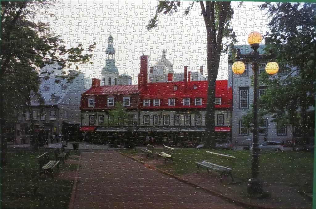 A park scene in Old Quebec with a red-roofed building, streetlights, and benches at twilight.