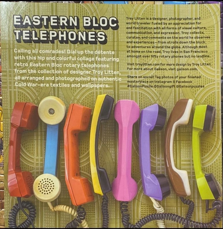 Retro Eastern Bloc rotary telephones in bright colors arranged on vintage wallpaper.