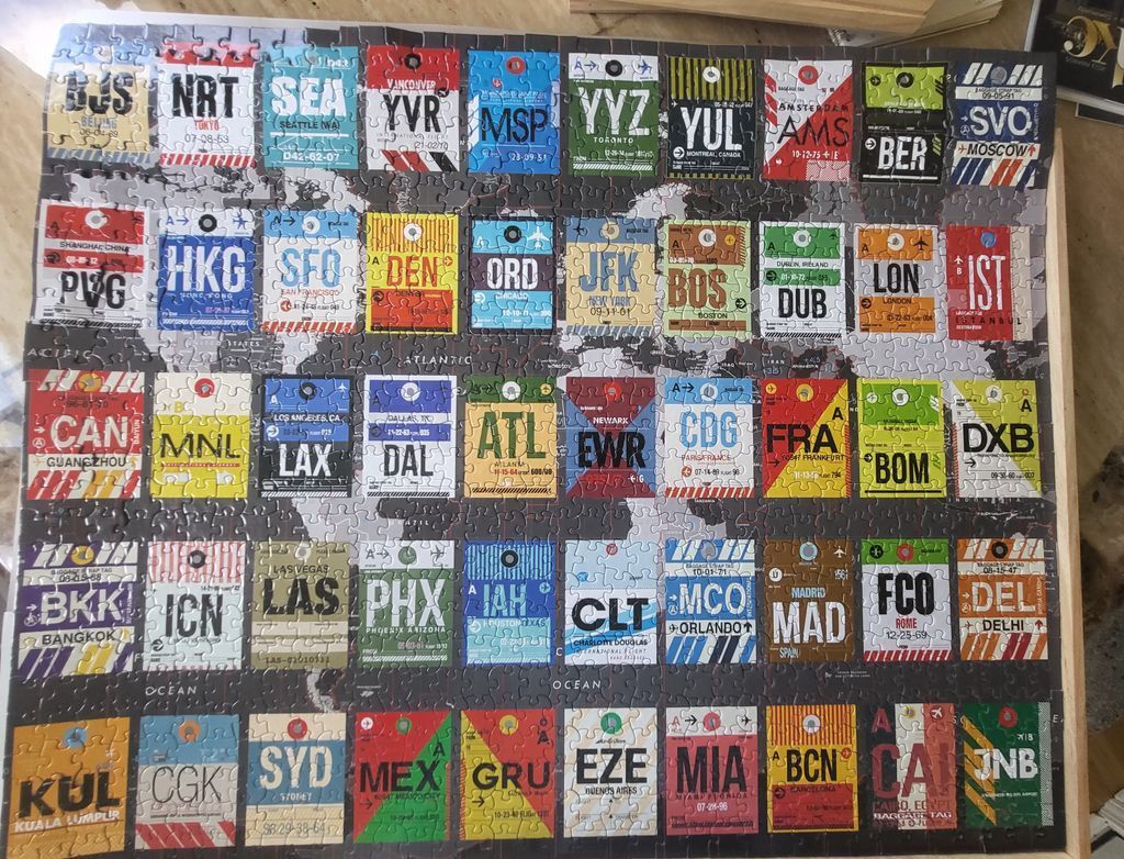 A collage of vintage international airport baggage tags arranged over a monochrome world map.