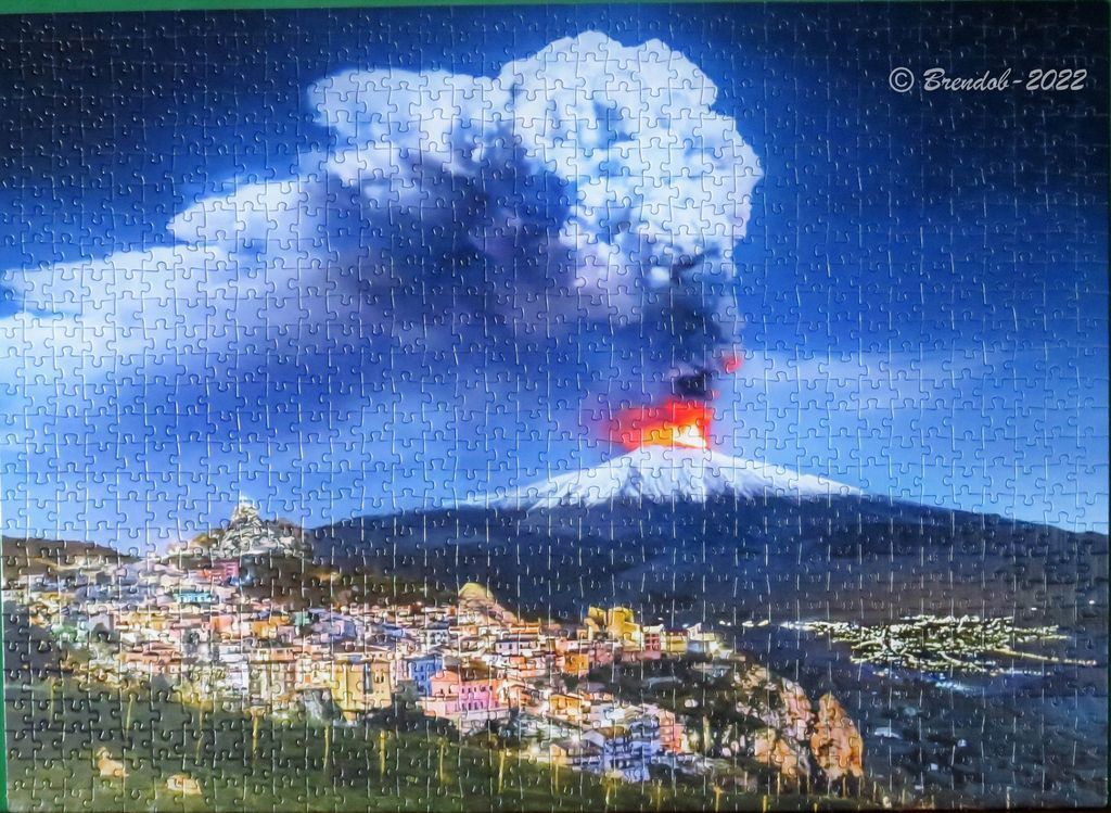Mount Etna erupting at night with a small town in the foreground.