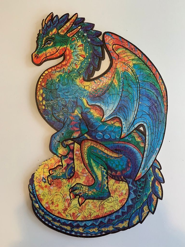 A vibrant, multi-coloured illustration of a fantasy dragon perched on a circular mound.